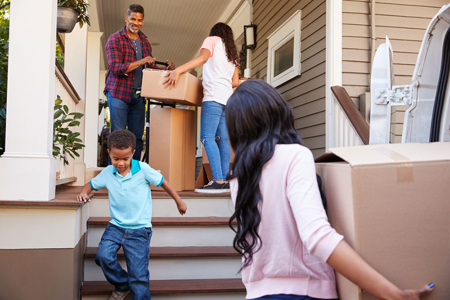 Happy family moving cardboard boxes into brand new house