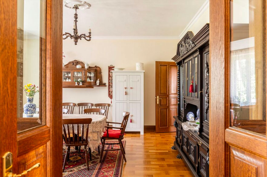 Beautiful dining room seen through open glass and wooden doors with a wood floor and dining table