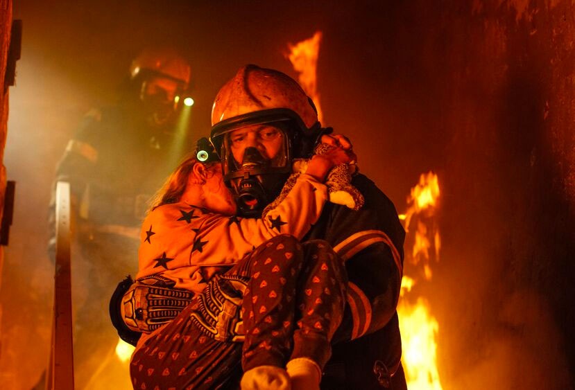 Firefighter carrying out a young girl from a burning building