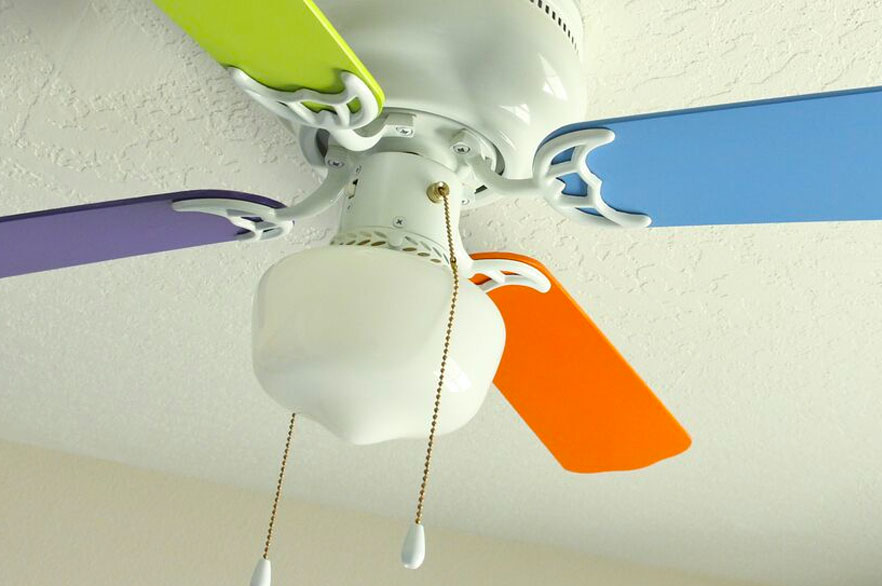 Ceiling fan in a nursery with four different colored fan blades