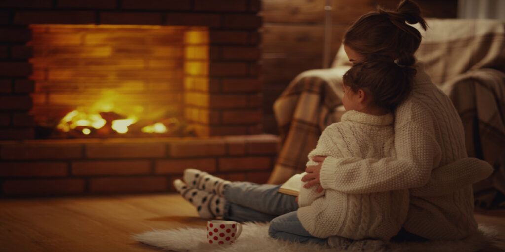 Mother and daughter sitting together in front of fireplace