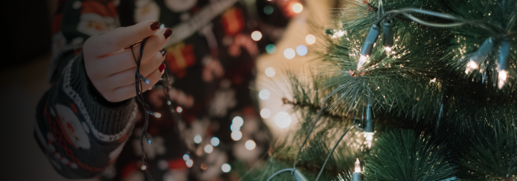 Woman's hand putting Christmas string lights on tree