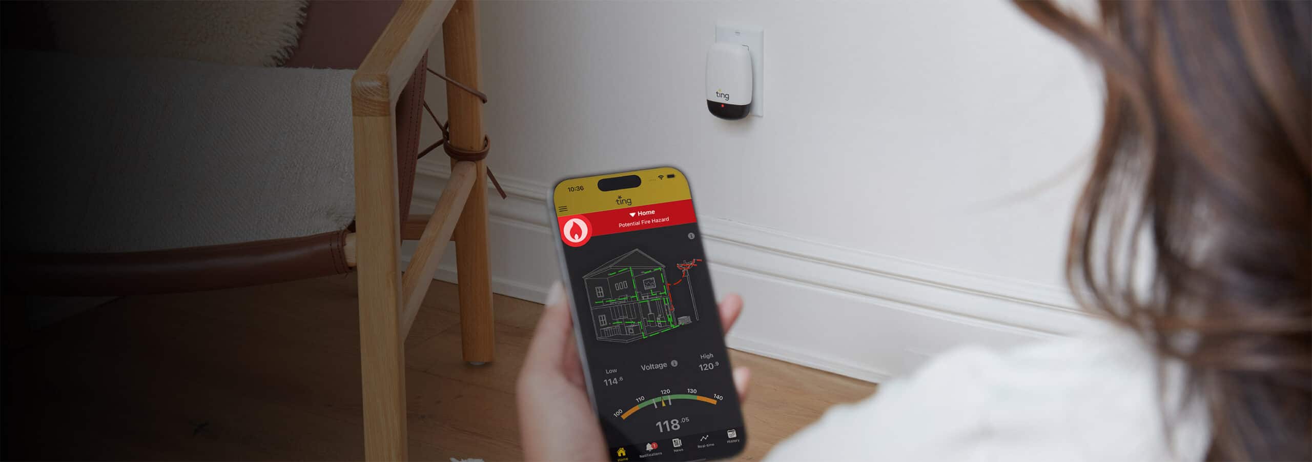 A woman holding a phone with the Ting Sensor app open showing a red fire hazard detected screen with Ting sensor plugged in in the background.