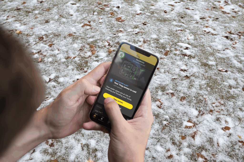 A person checking the Ting App on their mobile phone after receiving a frozen pipe alert.