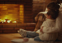 Mother and daughter sitting together in front of fireplace