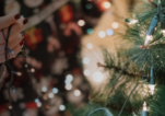 Woman's hand putting Christmas string lights on tree